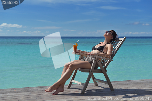 Image of Beautiful young woman with a drink by the sea