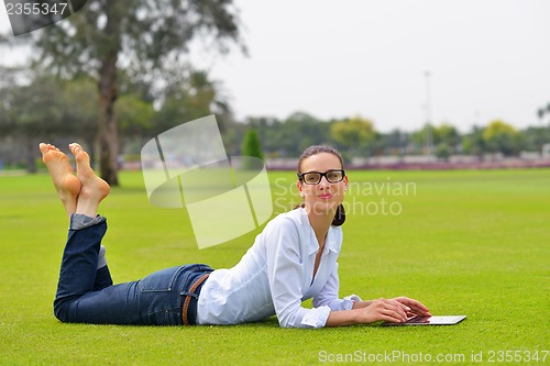 Image of Beautiful young woman with  tablet in park