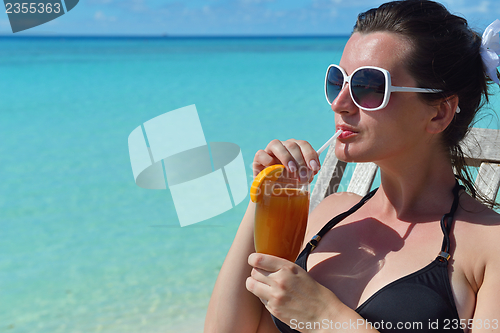 Image of Beautiful young woman with a drink by the sea