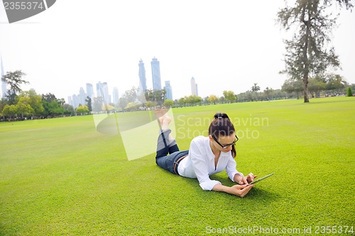 Image of Beautiful young woman with  tablet in park