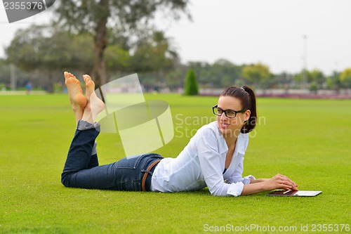 Image of Beautiful young woman with  tablet in park