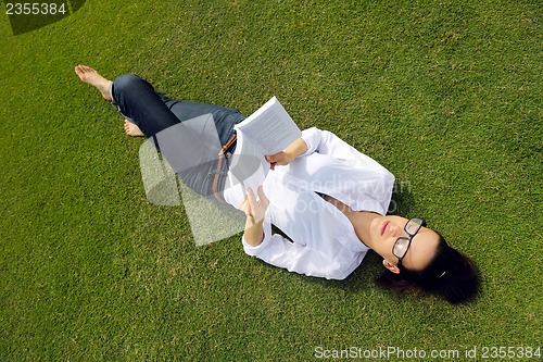 Image of Young woman reading a book in the park