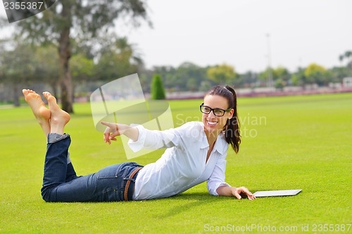 Image of Beautiful young woman with  tablet in park