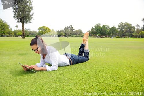 Image of Beautiful young woman with  tablet in park