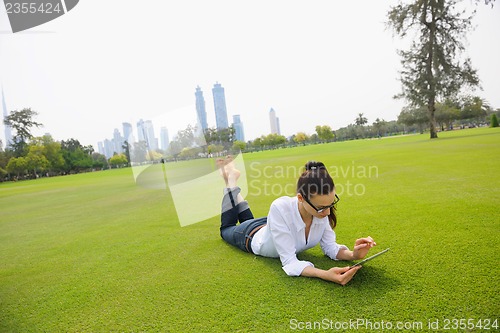 Image of Beautiful young woman with  tablet in park