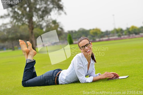 Image of Beautiful young woman with  tablet in park