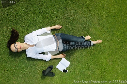 Image of Young woman reading a book in the park