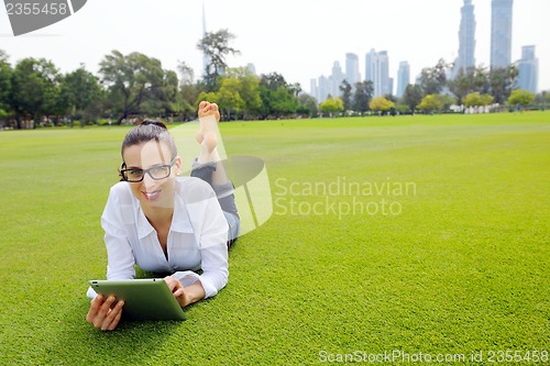 Image of Beautiful young woman with  tablet in park