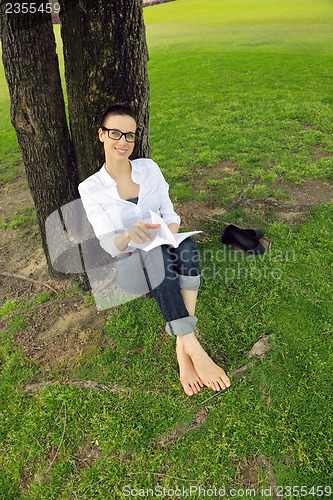 Image of Young woman reading a book in the park