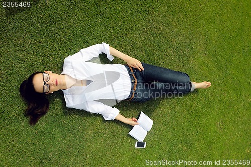 Image of Young woman reading a book in the park