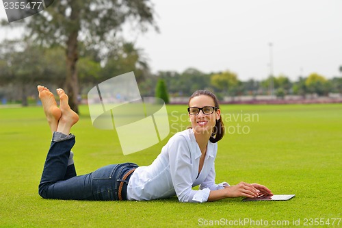 Image of Beautiful young woman with  tablet in park