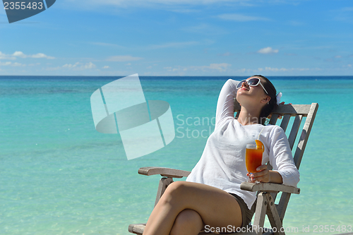 Image of Beautiful young woman with a drink by the sea