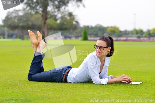 Image of Beautiful young woman with  tablet in park