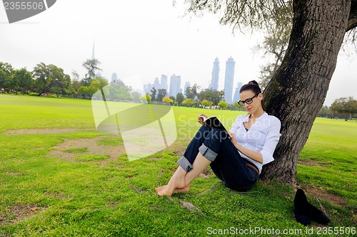 Image of Young woman reading a book in the park