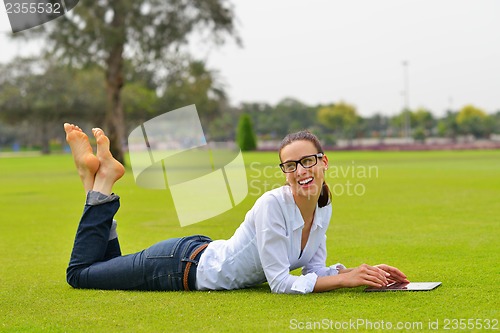 Image of Beautiful young woman with  tablet in park