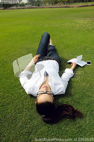 Image of Young woman reading a book in the park