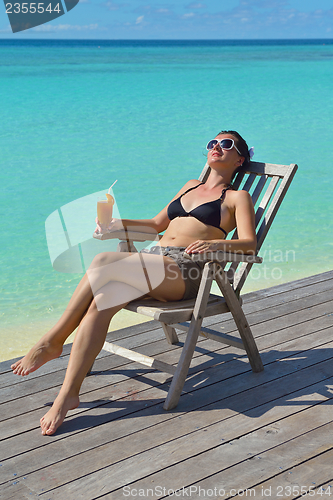 Image of Beautiful young woman with a drink by the sea