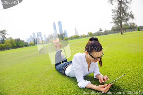 Image of Beautiful young woman with  tablet in park