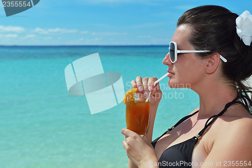 Image of Beautiful young woman with a drink by the sea