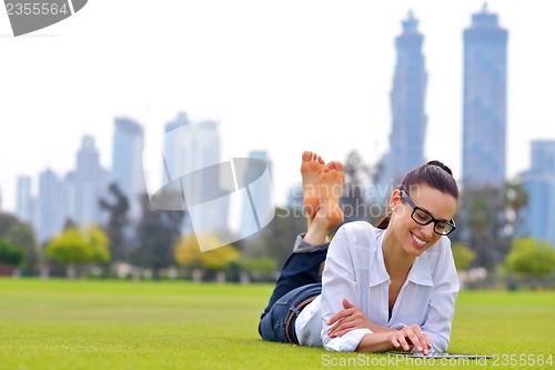 Image of Beautiful young woman with  tablet in park