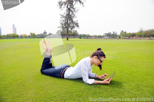 Image of Beautiful young woman with  tablet in park