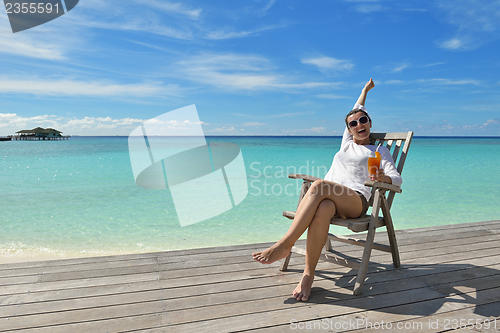 Image of Beautiful young woman with a drink by the sea