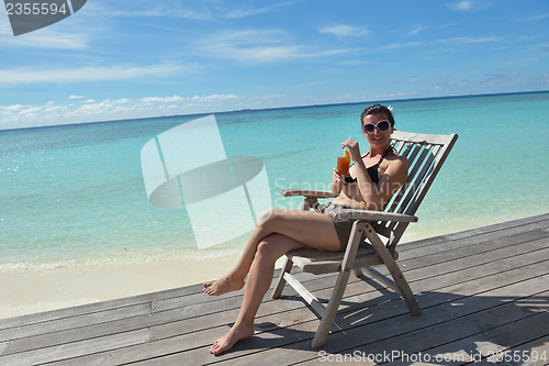 Image of Beautiful young woman with a drink by the sea