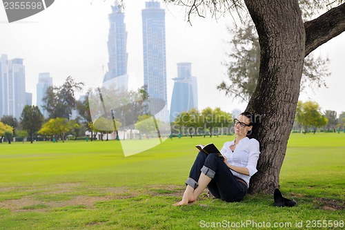 Image of Young woman reading a book in the park