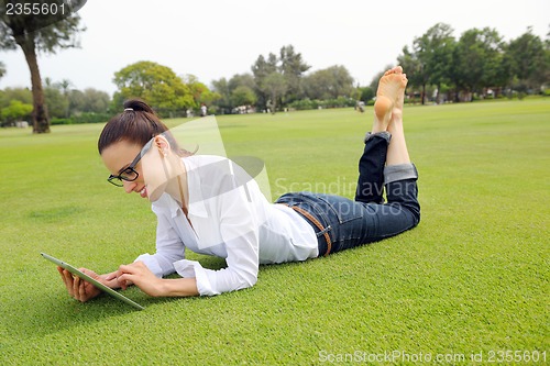 Image of Beautiful young woman with  tablet in park