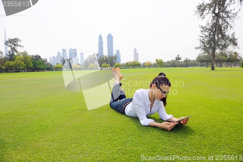 Image of Beautiful young woman with  tablet in park