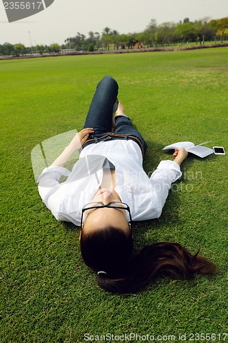 Image of Young woman reading a book in the park