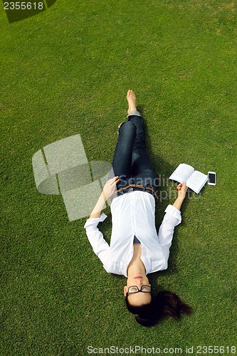 Image of Young woman reading a book in the park