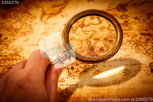 Image of Vintage magnifying glass lies on an ancient world map