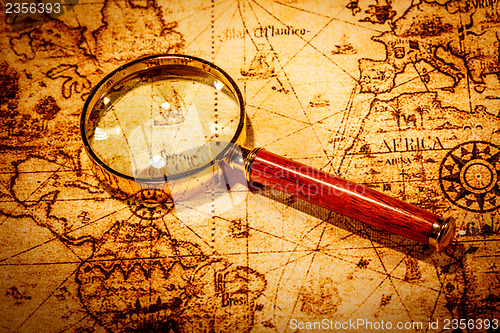 Image of Vintage magnifying glass lies on an ancient world map