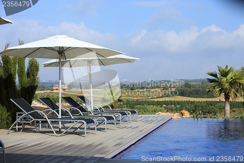 Image of Wooden deck with recliners and umbrellas