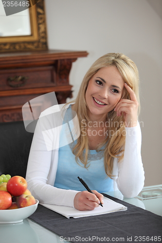 Image of Woman thinking as she writes correspondence