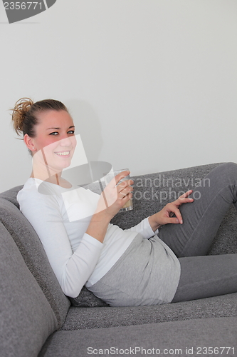 Image of Attractive woman relaxing on a sofa at home