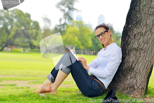 Image of Young woman reading a book in the park