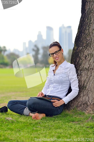 Image of Beautiful young woman with  tablet in park