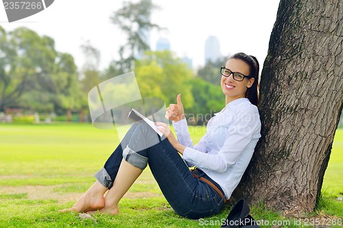 Image of Young woman reading a book in the park