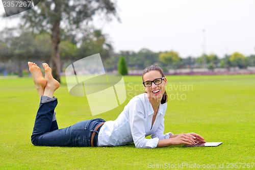 Image of Beautiful young woman with  tablet in park