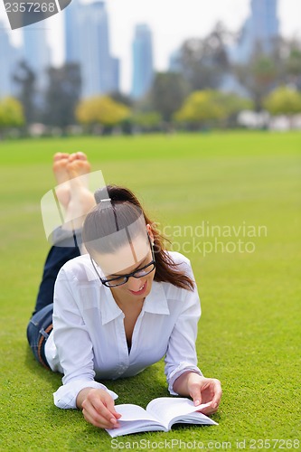 Image of Young woman reading a book in the park