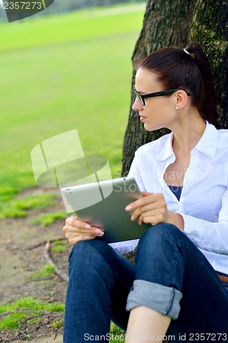 Image of Beautiful young woman with  tablet in park