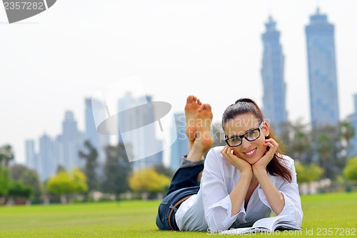 Image of Young woman reading a book in the park