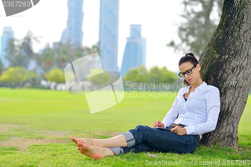 Image of Beautiful young woman with  tablet in park