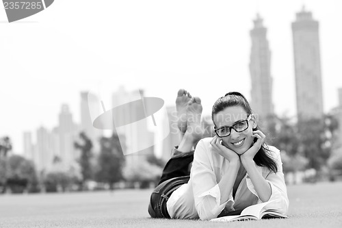 Image of Young woman reading a book in the park