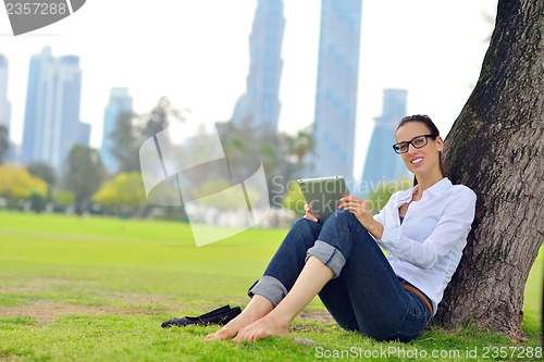 Image of Beautiful young woman with  tablet in park