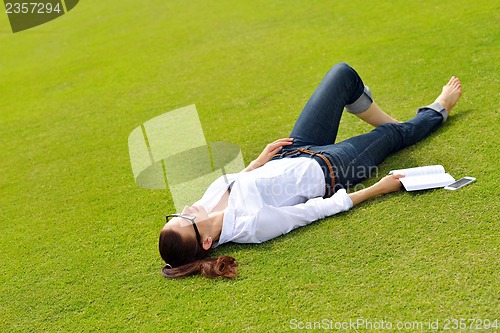 Image of Young woman reading a book in the park