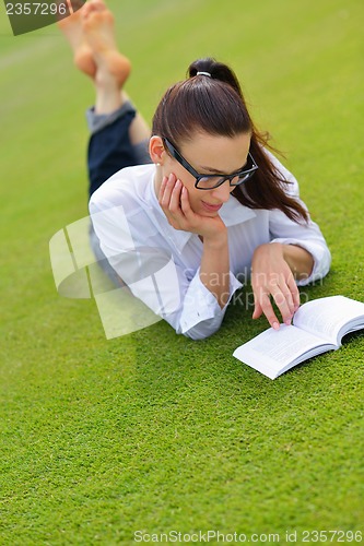 Image of Young woman reading a book in the park