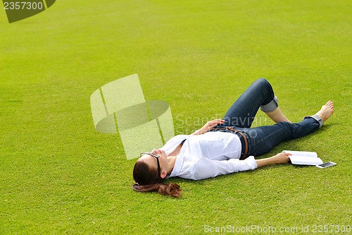 Image of Young woman reading a book in the park